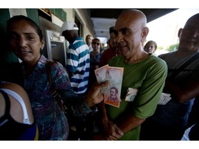 A woman shows a couple of new five "sovereign bolivar" Venezuelan bank notes, released from a government bank in Maracaibo, Venezuela, Tuesday, Aug. 21, 2018. The new currency will have two coins and paper denominations ranging from 2 up to 500. The lowest represents the buying power of 200,000 current bolivars while the highest stands in for 50 million.