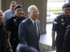 Former Malaysian Prime Minister Najib Razak, center, arrives at High Court of Malaya in Kuala Lumpur, Malaysia, Wednesday, Aug. 8, 2018. Najib will face a new charge of money laundering over a multibillion-dollar graft scandal at a state investment fund, the anti-corruption agency said. Najib in July pleaded not guilty to abuse of power and three counts of criminal breach of trust, just two months after the scandal led to his stunning election defeat.