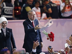 Turkey's President Recep Tayyip Erdogan, accompanied by his wife Emine, left, throws flowers to his supporters as he arrives to deliver a speech at his ruling Justice and Development Party (AKP) congress in Ankara, Turkey, Saturday, Aug. 18, 2018.