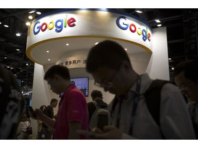 FILE - In this April 27, 2017, file photo, visitors use their smartphones in front of a booth for Google at the Global Mobile Internet Conference (GMIC) in Beijing. More than a dozen human rights groups have sent a letter dated Tuesday, Aug. 28, 2018, to Google urging the company not to offer censored internet search in China, amid reports it is planning to again begin offering the service in the giant Asian market.