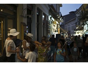 In this Friday, Aug. 17, 2018 photo, tourists walk in Plaka neighborhood of Athens. The one area of the economy that's flourishing is tourism, with officials projecting a record-high 32 million arrivals this year. Greeks, however, are finding it increasingly expensive to go on holiday in their own country, while a boom in short-term rentals in residential districts of Athens has driven rents beyond the reach of many locals.