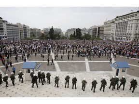 In this Wednesday, May 5, 2010 file photo, a riot police cordon secure the Greek Parliament in front of protestors in central Athens.  In a day of mass protests and rioting, three people die trapped in a burning bank.