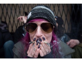 A woman smokes two joints during a sit-in as police officers raid the Cannabis Culture shop, in Vancouver, B.C., on Thursday March 9, 2017. Getting paid to smoke pot is no longer a toker's daydream. Toronto-based company AHLOT is offering $50 an hour to five so-called cannabis connoisseurs to sample various strains of marijuana.