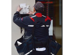 A mail carrier delivers mail in Ottawa, on Dec.11, 2013. The union representing thousands of Canada Post workers says it will stay at the bargaining table, averting a potential strike by mid-week.