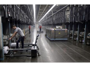 Workers exchange spools of thread as a robot picks up thread made from recycled plastic bottles at the Repreve Bottle Processing Center, part of the Unifi textile company in Yadkinville, N.C., on October 21, 2016. The Liberals have been told to consider taxing robots that displace workers, letting people pay their tax bill without cash, and work to prevent income inequality before it happens as part of a massive government effort to adapt to a rapidly changing workforce and stave off any strain it could cause on federal finances. Documents obtained by