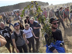 Protesters walk on a field close to the Hambach forest in Kerpen, Germany, Sunday, Sept. 16, 2018. Thousands of people are protesting against the expansion of a coal strip mine in western Germany that would entail the chopping down of an ancient forest.