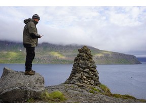 In this photo taken on Aug. 8, 2018, a local ranger for the Environment Agency of Iceland attempts to make a call from the unofficially named Telephone Mountain, in Vesteinn Runarsson, Iceland. Residents and outdoor enthusiasts in northwestern Iceland are communicating their desire to keep internet access out of the country's Hornstrandir peninsula.