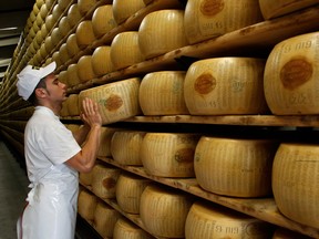 A worker selects a whole Parmigiano-Reggiano cheese from a storage rack in Italy. Some European cheesemakers say they are not getting the access to the Canadian market they were promised under CETA.