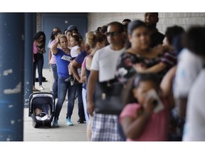 Residents stand in a block-long line outside a customer help center staffed by Columbia Gas of Massachusetts in Lawrence, Mass., Monday, Sept. 17, 2018. Dozens of homes were destroyed or damaged, a teenager was killed and dozens of people were injured in Lawrence, North Andover and Andover following a failure last week in the area natural gas delivery service. Federal officials say their investigation is partially focused on pressure sensors that were connected to a gas line that was being taken out of service shortly before the blasts.