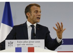 French President Emmanuel Macron delivers a speech on poverty to social aid workers in Paris, France, Thursday, Sept. 13, 2018. French President Emmanuel Macron has unveiled a 8-billion euro plan focusing on education and getting the unemployed back to work in an effort to combat poverty. Placard reads "make more for those who have less".