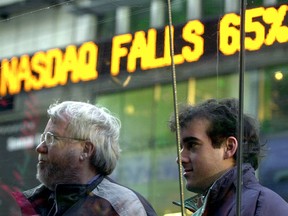 Men stands watching stock quotes from the windows of the Nasdaq on Dec. 20, 2000.
