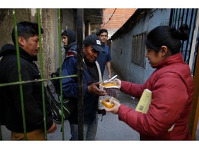 In this Sept. 6, 2018 photo, people line up for a small meal outside a soup kitchen at a community center in the Villa 1-11-14 shantytown on the outskirts of Buenos Aires, Argentina. Analysts say that poverty, which affects about a third of the population, will rise this year, and the economy will take a dive.