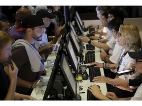 FILE - In this July 14, 2018, file photo, people, left, talk to tellers while placing bets at the Meadowlands Racetrack, in East Rutherford, N.J.   Dozens of states are rushing to capitalize on the U.S. Supreme Court lifting a federal ban on sports gambling.
