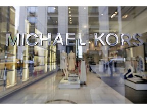 FILE- In this May 31, 2017, file photo the Michael Kors name adorns his store on Madison Avenue, in New York. Michael Kors is buying the Italian fashion house Gianni Versace in a deal worth more than $2 billion in a hard  charge into the world of high end fashion. The deal announced Tuesday, Sept. 25, 2018, follows the New York handbag maker's $1.35 billion acquisition last year of the high-end shoemaker Jimmy Choo.