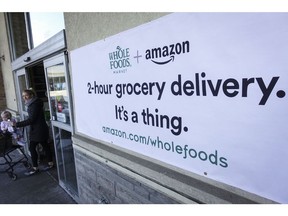 FILE - In this Feb. 8, 2018, file photo, a sign promoting the Amazon Prime Now delivery service is displayed outside a Whole Foods store, in Cincinnati. Amazon and Whole Foods are rolling out their grocery delivery service in several locations Wednesday, Sept. 26, while expanding it in other areas.