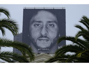 FILE- In this Sept. 5, 2018, file photo palm trees frame a large billboard on top of a Nike store that shows former San Francisco 49ers quarterback Colin Kaepernick at Union Square in San Francisco. Nike Inc. reports earnings Tuesday, Sept. 25.