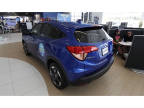 FILE- In this Aug. 30, 2018, photo, buyers sit in a cubicle near a 2018 HR-V on the floor of a Honda dealership in Highlands Ranch, Colo. On Tuesday, Sept. 25, the Conference Board releases its September index on U.S. consumer confidence.