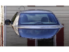 FILE- In this Monday, Sept. 17, 2018, a submerged car sits surrounded by water outside a home in a flooded neighborhood in Lumberton, N.C., in the aftermath of Hurricane Florence. As flooding continues in the Carolinas after Florence's massive rainfall, experts say high water will damage thousands of vehicles.