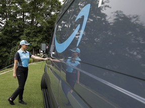 FILE- In this June 27, 2018, file photo, Parisa Sadrzadeh, a senior manager of logistics for Amazon.com, opens the door of an Amazon-branded delivery van at the request of a photographer in Seattle, following a media event for Amazon to announce a new program that lets entrepreneurs around the country launch businesses that deliver Amazon packages. Amazon says it has ordered 20,000 vans for its new delivery program. The online retailer says "tens of thousands" of individuals have applied for the program, and it had to up its van order to 20,000 from 4,500.