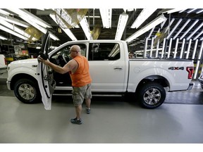 FILE- In this March 13, 2015, file photo, a worker inspects a new 2015 aluminum-alloy body Ford F-150 truck at the company's Kansas City Assembly Plant in Claycomo, Mo. Under pressure from U.S. safety regulators, Ford is recalling about 2 million F-150 pickups in North America because the seat belts can cause fires. The recall covers certain trucks from the 2015 through 2018 model years.