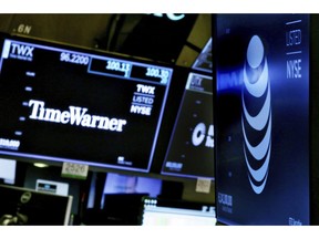 FILE - In this June 13, 2018, file photo, the logos for Time Warner and AT&T appear above alternate trading posts on the floor of the New York Stock Exchange. Defending court approval of its huge merger with Time Warner, AT&T is arguing the Trump Justice Department failed to show that the merger will raise wholesale prices for pay-TV programming and for consumers.