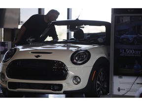 In this Thursday, Aug. 30, 2018, photo, a prospective buyer looks over a 2019 Cooper S convertible on the showroom floor of a Mini dealership in Highlands Ranch, Colo. On Friday, Sept. 14, the Commerce Department releases U.S. retail sales data for August.
