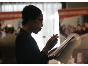 FILE- In this Jan. 30, 2018, file photo, Joana Dudley, of Lauderhill, Fla., looks at her list of job prospects at a JobNewsUSA job fair in Miami Lakes, Fla. U.S. employers likely hired at a healthy pace in August, emboldened by brisk consumer spending and an economy that keeps growing steadily.