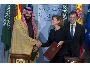 FILE - In this April 12, 2018 file photo, Saudi Arabia Crown Prince Mohammed bin Salman, left, and Spain's then Defense Minister Maria Dolores Cospedal shake hands after signing bi-lateral agreements in the presence of the then Prime Minister of Spain Mariano Rajoy, right, at the Moncloa Palace in Madrid. Spain will go ahead with a shipment of precision bombs to Saudi Arabia after consultations with his long-time commercial ally Riyadh, officials said Thursday Sept. 13, 2018, reversing a previous decision and angering rights organizations who claim the weapons could harm civilians in Yemen.