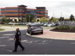 A policer officer walks near the scene where a shooting was reported at a software company in the background in Middleton, Wis., Wednesday, Sept. 19, 2018. Multiple were reported to have been shot.
