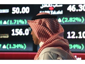 FILE - In this June 15, 2015, file photo, a Saudi man walks through the Tadawul Saudi Stock Exchange in Riyadh, Saudi Arabia. Saudi Arabia's sovereign wealth fund invested over $1 billion on Monday, Sept. 17, 2018, in an American electric car manufacturer just weeks after Tesla CEO Elon Musk earlier claimed the kingdom would help his own firm go private.