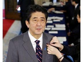 FILE - In this Dec. 26, 2012, file photo,  then Japan's prime-minister-to-be Shinzo Abe has his diet lapel pin attached to his jacket as he arrives at the parliament for the special diet session in Tokyo. Abe is expected to be re-elected by his ruling Liberal Democratic Party to a third term as its leader on Thursday, Sept. 20, 2018, paving the way for him to serve as prime minister for up to three more years. (AP Photo/Kyodo News)/Kyodo News via AP)