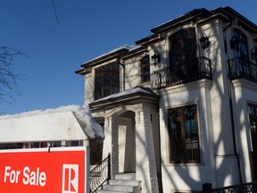 A for sale sign is shown outside a house in Vancouver. Prospects for the city’s housing market, which has some of the most expensive homes in the world, has grown more precarious, according to a analyst poll.