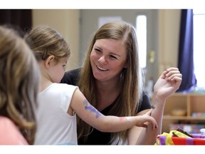 In this photo taken Monday, Aug. 27, 2018, director Jenny Cimbalnik talks with a child at the Wallingford Child Care Center in Seattle. A dire workforce crisis in a booming U.S. economy is forcing many in the child care industry to turn to business tactics more closely resembling Wall Street than Sesame Street. Non-compete and "hold-harmless" legal agreements, college tuition incentives for workers and steep waiting-list fees for parents are fast becoming the norm.