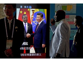 African delegates walk by a screen panel showing a footage of Chinese President Xi Jinping with Ethiopia's Prime Minister Abiy Ahmed ahead of the Forum on China-Africa Cooperation in Beijing, Monday, Sept. 3, 2018. African leaders will likely press their Chinese hosts at a conference this week to help narrow their trade deficits with Beijing by shifting more manufacturing to their continent, the chief executive of the biggest African bank said.