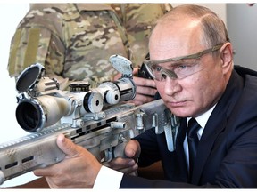 Russian President Vladimir Putin aims a sniper rifle during a visit to the Patriot military exhibition center outside Moscow, Russia, Wednesday, Sept. 19, 2018. Putin chaired a meeting that focused on new arms programs.