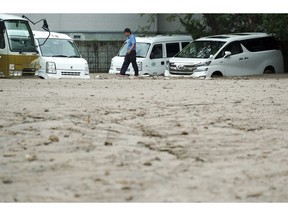 A worker walks past cars half buried in mud caused by ground liquefaction after a powerful earthquake in Kiyota ward of Sapporo, Hokkaido, northern Japan, Saturday, Sept. 8, 2018. Thursday's powerful earthquake hit wide areas on Japan's northernmost main island of Hokkaido. Some parts of the city were severely damaged, with houses atilt and roads crumbled or sunken. A mudslide left several cars half buried, and the ground subsided in some areas, leaving drainpipes and manhole covers protruding by more than a meter (yard) in some places.