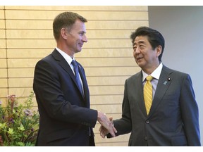 British Foreign Secretary Jeremy Hunt, left, shakes hands with Japanese Prime Minister Shinzo Abe during his courtesy call at his official residence in Tokyo Tuesday, Sept. 18, 2018.