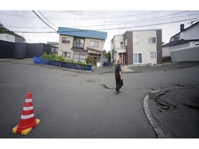 A resident walks by damaged houses in Kiyota, outskirts of Sapporo city, Hokkaido, northern Japan, Friday, Sept. 7, 2018. A powerful earthquake hit wide areas on Japan's northernmost main island of Hokkaido early Thursday, triggering landslides as well as causing the loss of power.