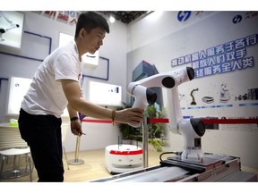 In this Aug. 15, 2018, photo, a visitor looks at a robotic manufacturing arm from Chinese robot maker Han's Robots at the World Robot Conference in Beijing. The head of China's patent and copyright agency is defending what he says are gains in fighting violations - once a chronic complaint by China's trading partners - in a new effort to defuse a tariff war with Washington.