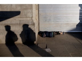 A man sleeps in front of a closed shop at the Retiro station, in Buenos Aires, Argentina, Tuesday, Sept. 25, 2018. Argentine labor unions stage a nationwide general strike Tuesday, to protest recent government measures and demand solutions to the country's economic crisis.