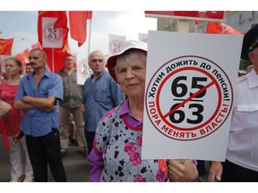 FILE - in this file photo taken on Saturday, July 28, 2018, an elderly woman holds a poster reads "Want to Retire, it's time to change the authority!" during a rally protesting retirement age hikes in Moscow, Russia. Tens of thousands of demonstrators have rallied throughout Russia to protest plans to substantially hike the age at which Russian men and women can receive their state retirement pensions. (AP Photo)