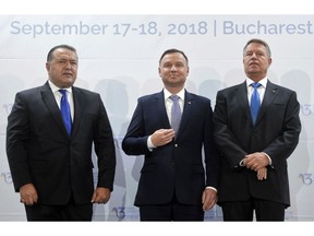 Polish President Andrzej Duda, center, poses next to Romanian counterpart Klaus Iohannis, right, and the head of Romania's Chamber of Commerce and Industry at the opening of the Three Seas Initiative in Bucharest, Romania, Monday, Sept. 17, 2018. U.S. President Donald Trump has reaffirmed Washington's support for a business summit that aims to boost connectivity in Eastern Europe and improve ties between the region and the U.S. and European Union.