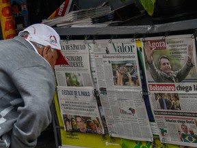 A man reads a newspaper at a stall a day after Jair Bolsonaro won the Brazilian presidential election, in Sao Paulo, Brazil.