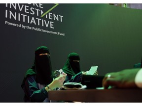 Saudi employees print badges of participants of the Future Investment Initiative conference, which kicks off Tuesday, in Riyadh, Saudi Arabia, Monday, Oct. 22, 2018. Saudi Arabia is moving ahead with plans to hold the glitzy investment forum, despite some of its most important speakers pulling out in the global outcry over the killing of Saudi journalist Jamal Khashoggi.