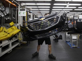 An employee carries a General Motors Co. (GM) Chevrolet bumper at the Magna International Inc. Polycon Industries auto parts manufacturing facility in Guelph, Ontario. Shares of Canadian auto suppliers are up on new trade deal USMCA.