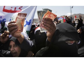 FILE - In this Oct. 17, 2011, file photo, a female protestor displays the local currency as a symbol of poverty during a demonstration demanding the resignation of Yemen's President Ali Abdullah Saleh in Sanaa, Yemen. Saudi Arabia has given a $200 million cash infusion to Yemen's Central Bank on Oct. 2, 2018, to shore up its reserves after the war-torn country's currency went into freefall over the past few weeks.