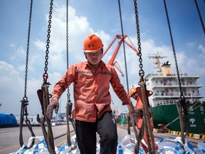 Workers unloading bags of chemicals at a port in Zhangjiagang in China's eastern Jiangsu province. The IMF on Tuesday cut its global growth forecasts due to an escalating U.S.-China trade war and growing financial strains on emerging markets.