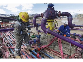 In this March 29, 2013 file photo, workers tend to a well head during a hydraulic fracturing operation at an Encana Oil & Gas (USA) Inc. gas well outside Rifle, in western Colorado. Encana Corp. has an agreement to sell its San Juan assets in New Mexico to a Denver-based company for the equivalent of nearly $615 million.