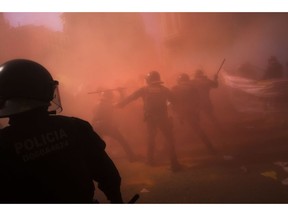 Catalan police officers clash with pro independence demonstrators on their way to meet demonstrations by members and supporters of National Police and Guardia Civil, as coloured powder is seen in the air after being thrown by protesters, in Barcelona on Saturday, Sept. 29, 2018.