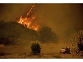 FILE - In this Dec. 9, 2017 file photo, a fire engine passes flames as a wildfire burns along Santa Ana Road near Ventura, Calif. Southern California Edison said Tuesday, Oct. 30, 2018, its equipment likely sparked one of two ignition points for Thomas fire, a wildfire that tore through California's central coast last year.